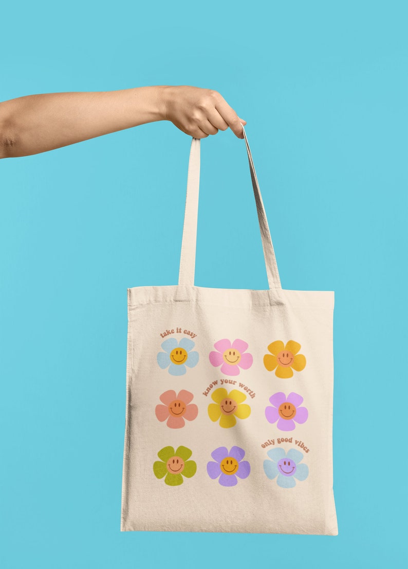 May include: A white canvas tote bag with colorful flower designs and the text "take it easy", "know your worth", and "only good vibes".