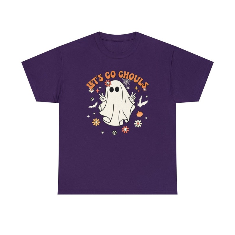 May include: Purple short-sleeved t-shirt with a white ghost wearing a flower crown and peace signs. The text "Let's Go Ghouls" is in orange and yellow letters.