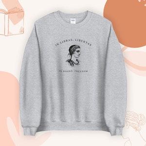 May include: Grey sweatshirt with a black and white illustration of a woman's head and the text "In Libras Libertas, In Books Freedom".