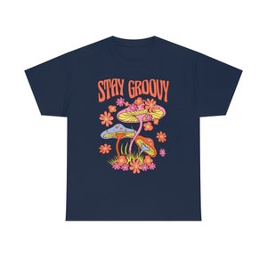 May include: Navy blue t-shirt with a colorful graphic of mushrooms and flowers. The text "STAY GROOVY" is printed in orange above the illustration. The design features yellow, pink, orange, and blue elements.