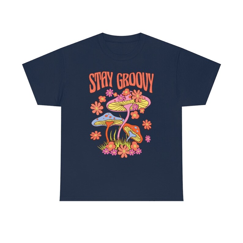 May include: Navy blue t-shirt with a colorful graphic of mushrooms and flowers. The text "STAY GROOVY" is printed in orange above the illustration. The design features yellow, pink, orange, and blue elements.