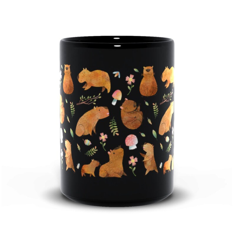 May include: Black ceramic mug with a repeating pattern of capybaras, mushrooms, and flowers. The capybaras are brown and white and are in various poses. The mushrooms are red and white with white spots. The flowers are pink and yellow.