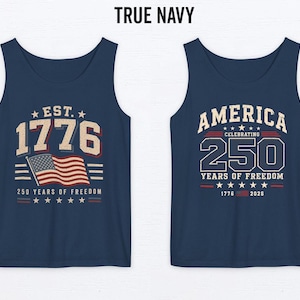 以下が含まれることがあります： 2 つのネイビーブルーのタンクトップ。1 つはアメリカ国旗と「EST. 1776」と「250 YEARS OF FREEDOM」と書かれています。もう 1 つは「AMERICA CELEBRATING 250 YEARS OF FREEDOM 1776-2026」と書かれています。