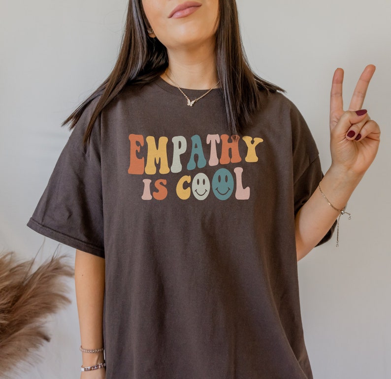May include: A brown t-shirt with the text "EMPATHY IS COOL" in colourful letters with smiley faces.