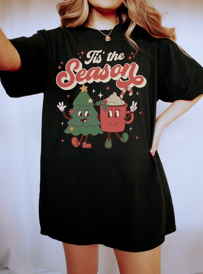 May include: Black t-shirt with a retro-style graphic of a Christmas tree and a mug with the text "Tis' the Season".