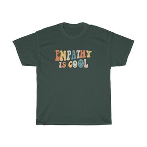May include: A dark green t-shirt with the text "EMPATHY IS COOL" in rainbow colours with smiley faces.