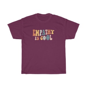 May include: A maroon t-shirt with the text "EMPATHY IS COOL" in rainbow colours with smiley faces.