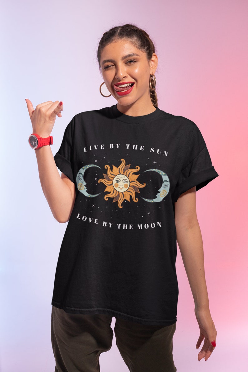 May include: Black t-shirt with a graphic of a sun and moon with the text "Live by the sun, love by the moon".