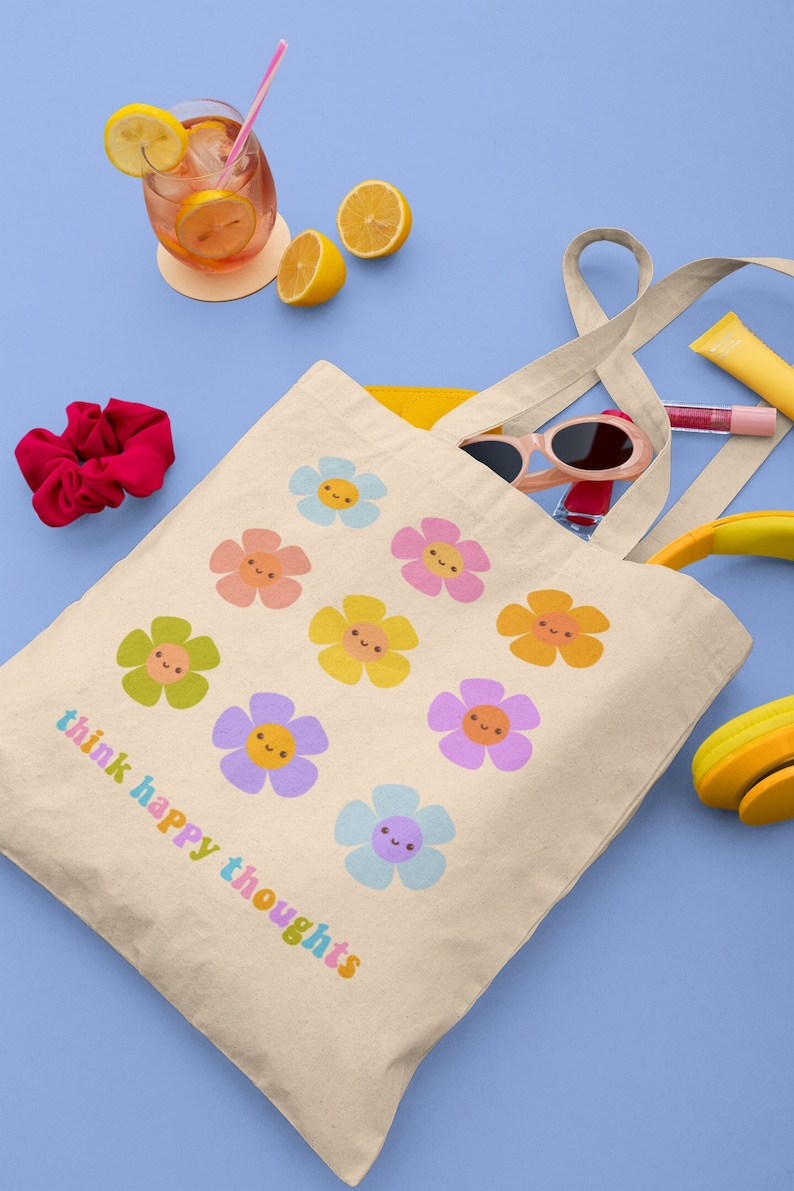 Pu&ograve; includere: Una borsa tote beige con il testo "think happy thoughts" stampato in colori arcobaleno. La borsa presenta un motivo di fiori colorati con facce sorridenti.
