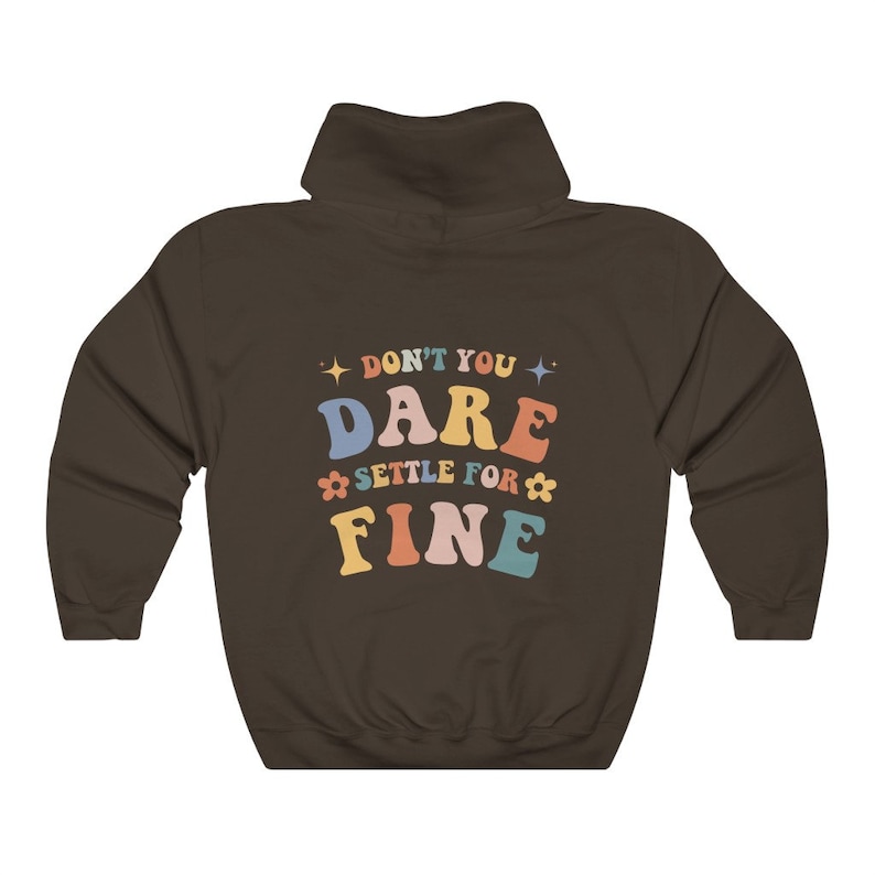 Puede incluir: Sudadera con capucha marr&oacute;n con el texto "Don't you dare settle for fine" en letras de colores.