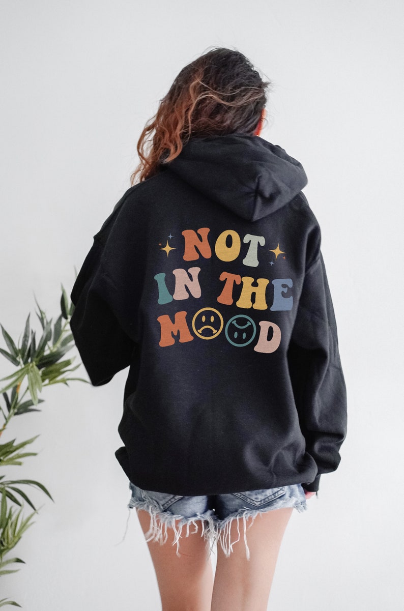 Pu&ograve; includere: Felpa con cappuccio nera con il testo "NOT IN THE MOOD" in colori arcobaleno sul retro.
