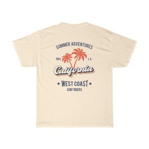 May include: A beige t-shirt with a graphic print of palm trees and the text "Summer Adventures 1982 California West Coast Surf Riders L.A."