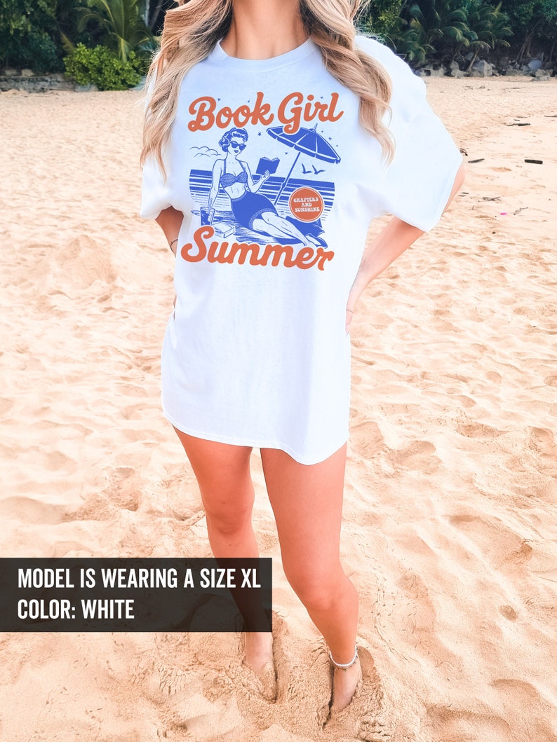 K&ouml;nnte beinhalten: Wei&szlig;es T-Shirt mit einer blauen und orangenen Grafik einer Frau, die ein Buch am Strand liest, mit dem Text "Book Girl Summer" und "Chapters and Sunshine" in einem Kreis.