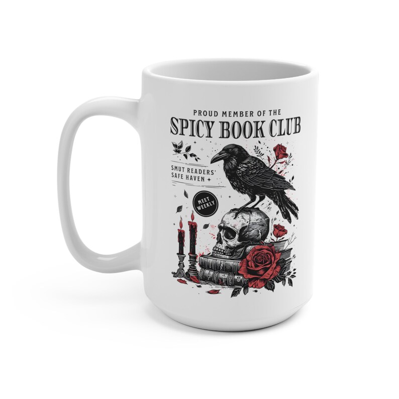Puede incluir: Taza de cer&aacute;mica blanca con una ilustraci&oacute;n en blanco y negro de un cuervo posado sobre un cr&aacute;neo con una pila de libros debajo. El texto "Proud Member of the Spicy Book Club" est&aacute; en la parte superior de la taza. El texto "Smut Readers' Safe Haven + Meet Weekly" est&aacute; debajo de la ilustraci&oacute;n.