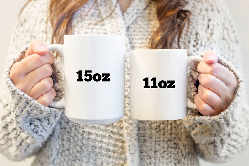 May include: Two white ceramic mugs with black text. The larger mug says "15oz" and the smaller mug says "11oz".