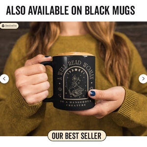 Pode incluir: Uma caneca de cer&acirc;mica preta com um design dourado que diz "Uma mulher bem lida &eacute; uma criatura perigosa". A caneca apresenta um livro, flores e uma lua crescente.