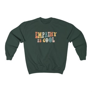 May include: A dark green sweatshirt with the text "EMPATHY IS COOL" in rainbow colors with smiley faces.