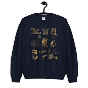 Puede incluir: Sudadera azul marino con un estampado gr&aacute;fico dorado de varias ilustraciones, incluyendo libros, un sol, una luna, una taza y una columna. Las ilustraciones son de estilo vintage.