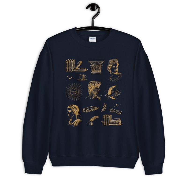 Puede incluir: Sudadera azul marino con un estampado gr&aacute;fico dorado de varias ilustraciones, incluyendo libros, un sol, una luna, una taza y una columna. Las ilustraciones son de estilo vintage.