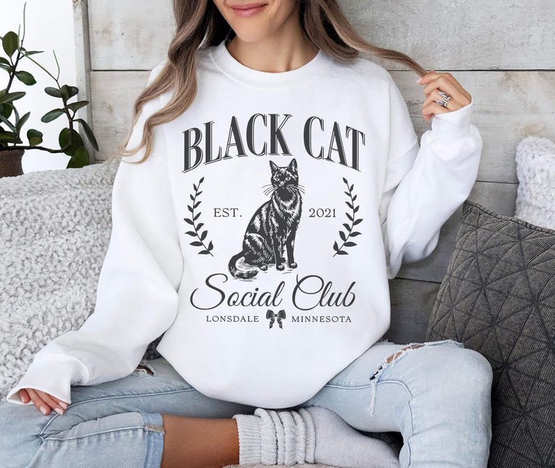May include: White sweatshirt with a black cat graphic and the text "Black Cat Social Club Est. 2021 Lonsdale Minnesota".