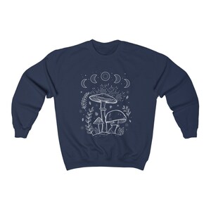 May include: Navy blue sweatshirt featuring a white outline of mushrooms and a crescent moon design. The text "Shroom Queens" is printed on the sweatshirt.