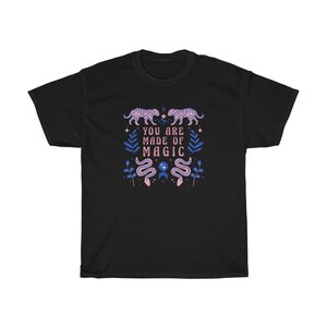 May include: Black t-shirt with a pink and blue design featuring tigers, snakes, and stars. The text "You are made of magic" is printed on the shirt.