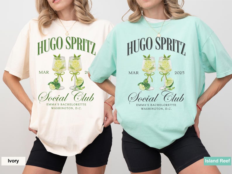 May include: Two white t-shirts with a green and black graphic design. The graphic features the text "HUGO SPRITZ" and two glasses of a lime-colored drink with lime slices. The text "MAR 20" and "MAR 2025" are also included in the design. The text "Social Club" is below the glasses and the text "EMMA'S BACHELORETTE WASHINGTON, D.C." is below that. The t-shirt on the left is ivory and the t-shirt on the right is light blue.