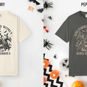 May include: Two short-sleeve crew neck t-shirts, one in ivory and one in pepper gray. Both feature a black graphic print of three witches around a cauldron with the text "GOD FORBID WOMEN HAVE HOBBIES" arched above and printed below the illustration.