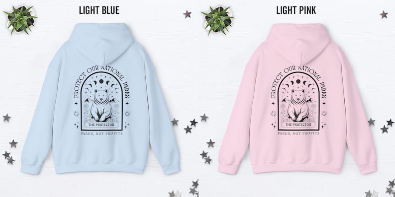 May include: Light blue and light pink hoodies with a graphic on the back. The graphic features a bear inside an arch with the text "PROTECT OUR NATIONAL PARKS" and "THE PROTECTOR PARKS, NOT PROFITS".
