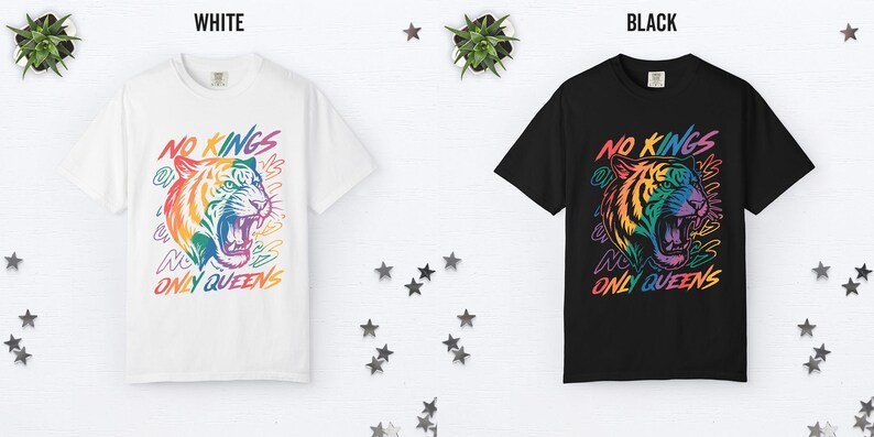 May include: White and black t-shirts with a colorful tiger graphic. The tiger has rainbow-colored fur and an open mouth. The text "NO KINGS ONLY QUEENS" is above and below the tiger.