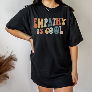 May include: Black oversized t-shirt with the text "EMPATHY IS COOL" in rainbow colours with smiley faces.