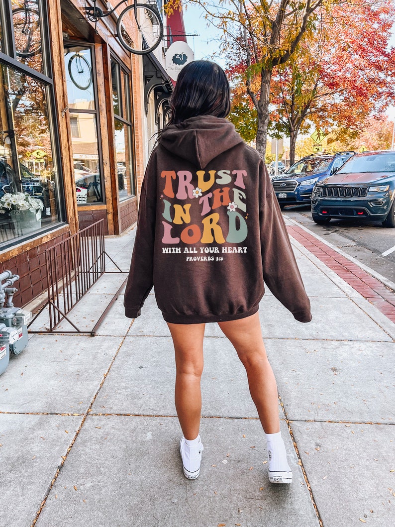 May include: Brown hooded sweatshirt with the text "TRUST IN THE LORD WITH ALL YOUR HEART PROVERBS 3:5" in colorful retro lettering.