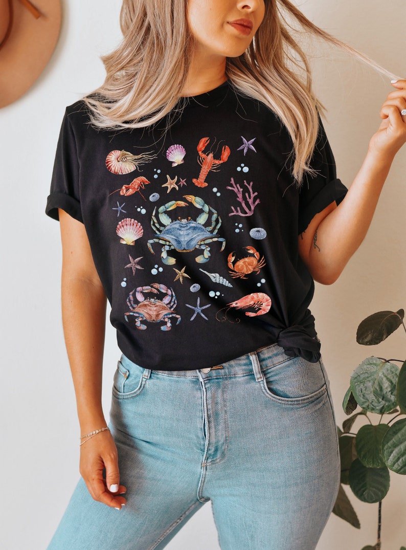 May include: A black t-shirt with a watercolor design of various sea creatures, including crabs, lobsters, starfish, and seashells.