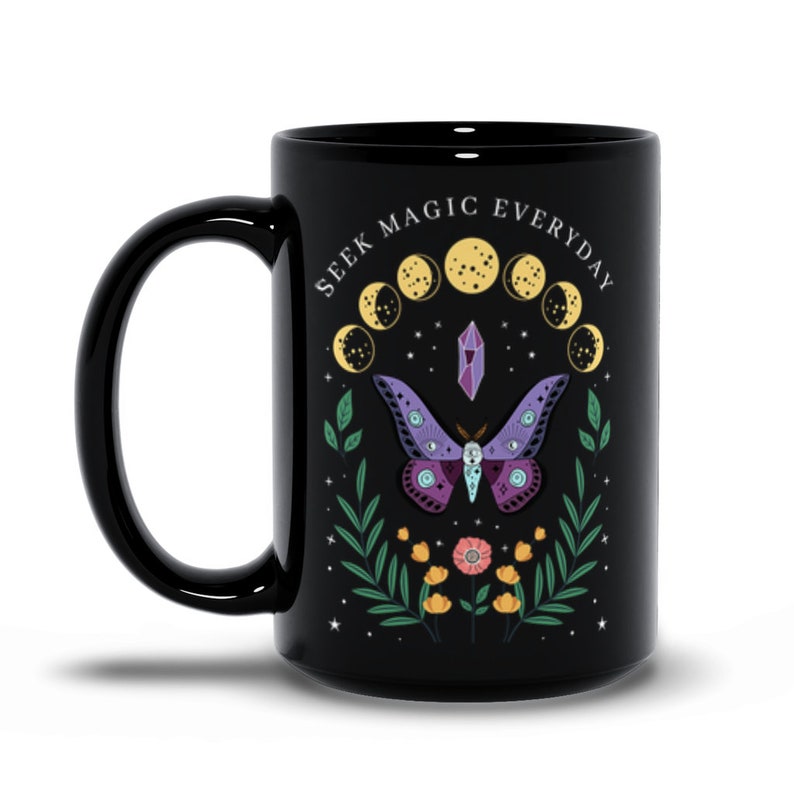May include: Black ceramic mug with a white design featuring a purple and pink butterfly, a crystal, and a crescent moon phase. The text "SEEK MAGIC EVERYDAY" is printed around the design.