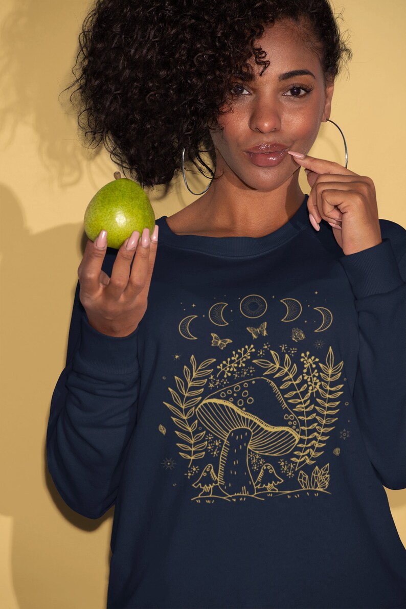 Op de afbeelding: Een marineblauw sweatshirt met een gouden afbeelding van een paddenstoel, bladeren en manen. De tekst "Shroom Queens" staat onderaan de afbeelding gedrukt.