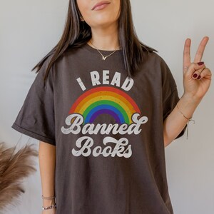 May include: A dark brown t-shirt with a rainbow and the text "I Read Banned Books" in a retro font.