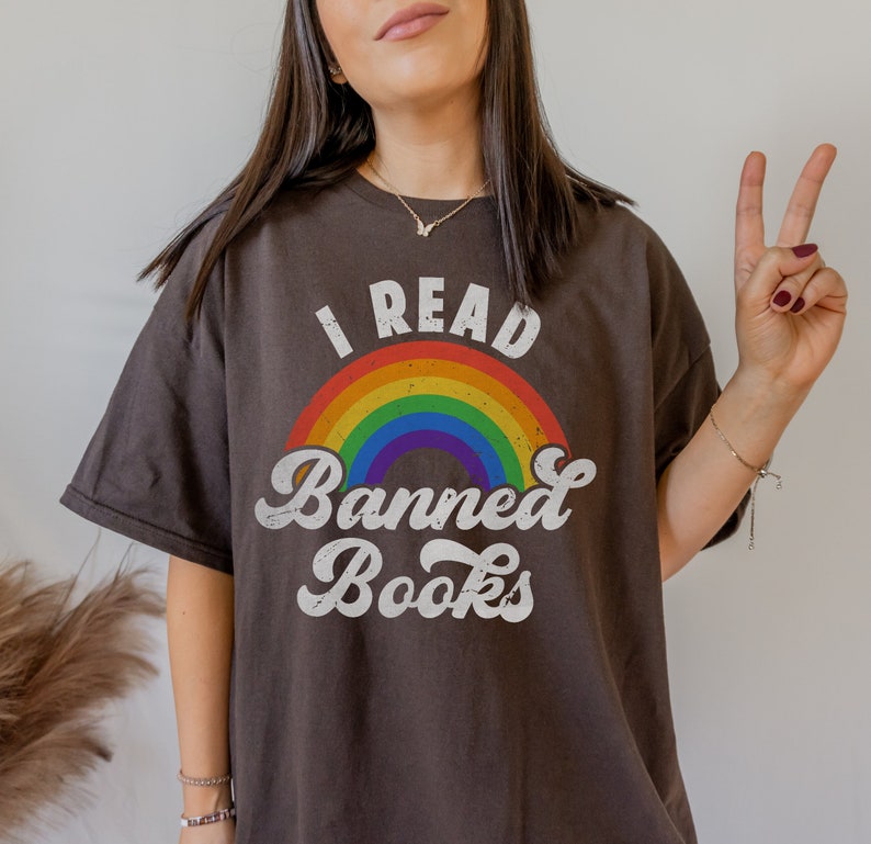 May include: A dark brown t-shirt with a rainbow and the text "I Read Banned Books" in a retro font.