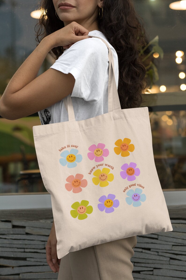 May include: A beige tote bag with a colorful floral design and the text "take it easy", "know your worth", and "only good vibes".