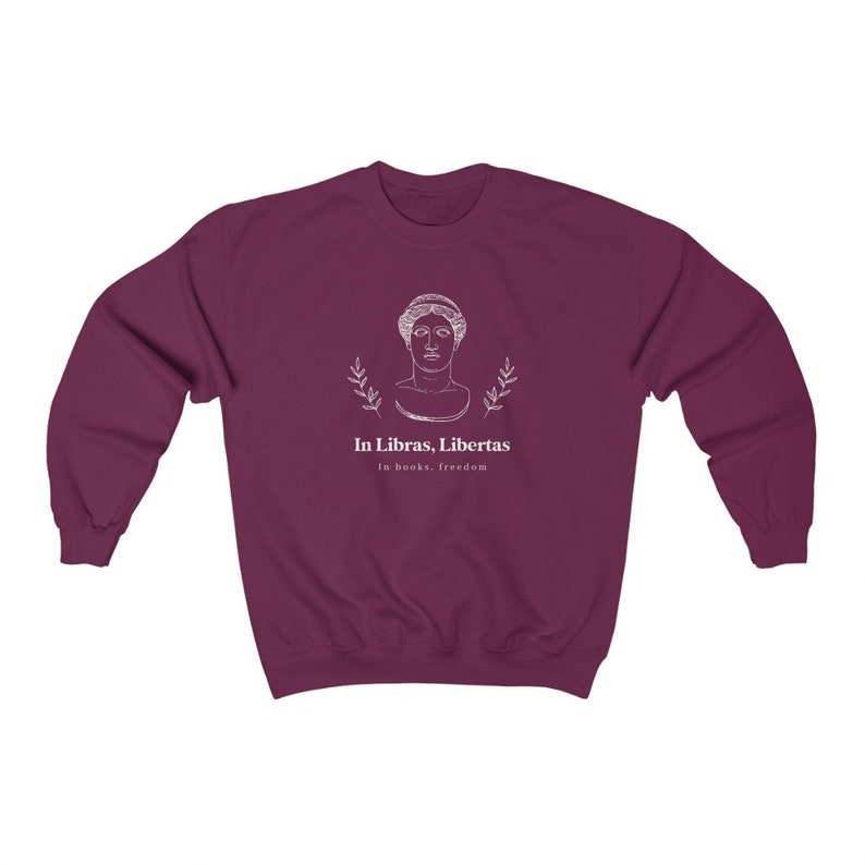 May include: Burgundy sweatshirt with a white graphic of a woman's bust with laurel branches and the text "In Libras, Libertas" and "In books, freedom".