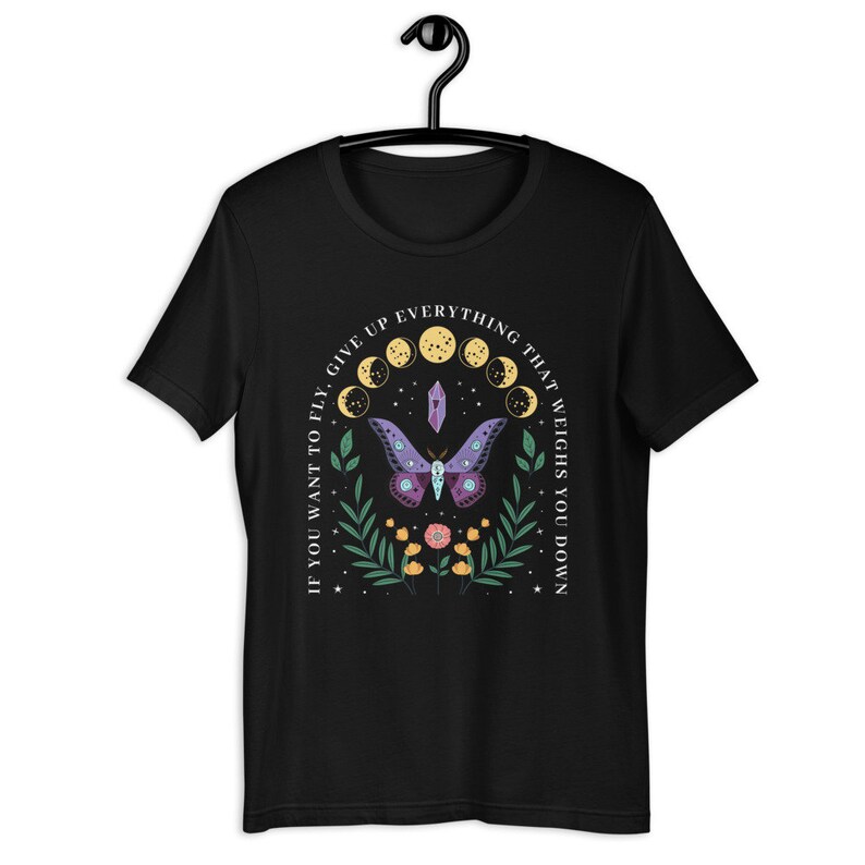 May include: Black t-shirt with a graphic of a purple and blue moth with a crystal and moon phases. The text "If you want to fly, give up everything that weighs you down" is printed around the graphic.