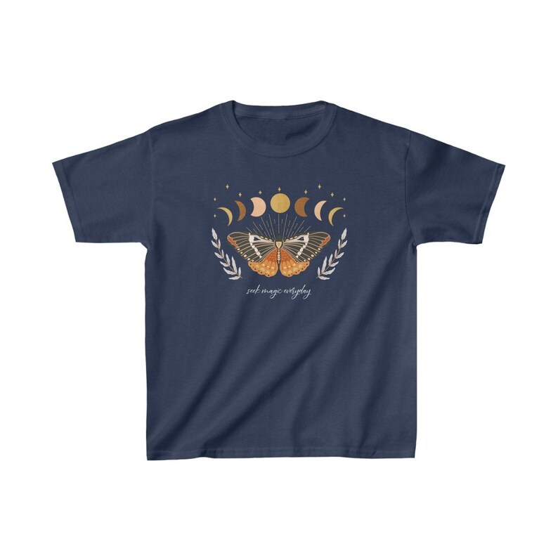 Peut inclure: T-shirt bleu marine avec un motif de papillon avec des phases de lune et des &eacute;toiles. Le texte "seek magic everyday" est imprim&eacute; sous le papillon.