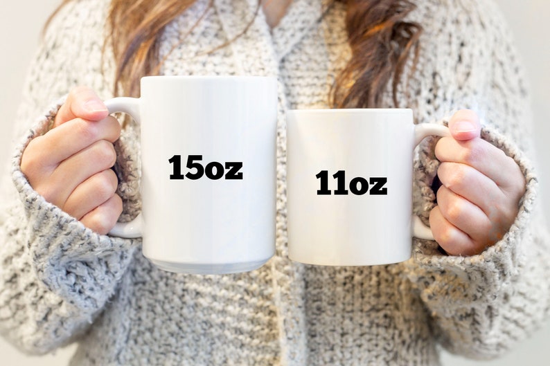 May include: Two white ceramic mugs with black text. The larger mug says "15oz" and the smaller mug says "11oz".