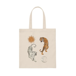 Op de afbeelding: Een beige tote bag met een witte tijger, een oranje tijger, een zon en een maanontwerp.