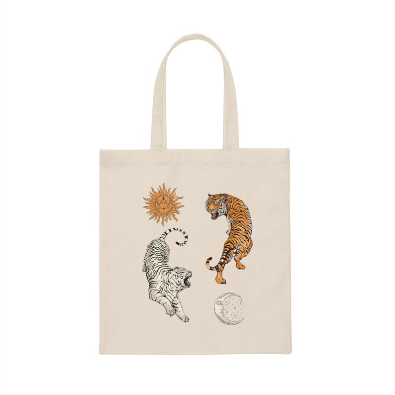 Op de afbeelding: Een beige tote bag met een witte tijger, een oranje tijger, een zon en een maanontwerp.