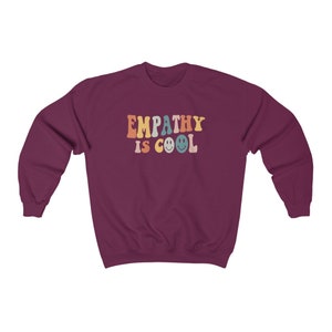 May include: A maroon sweatshirt with the text "EMPATHY IS COOL" in rainbow colors with smiley faces.