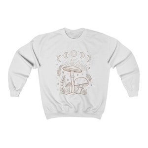 May include: White sweatshirt featuring a brown line drawing of mushrooms and a crescent moon phase design.