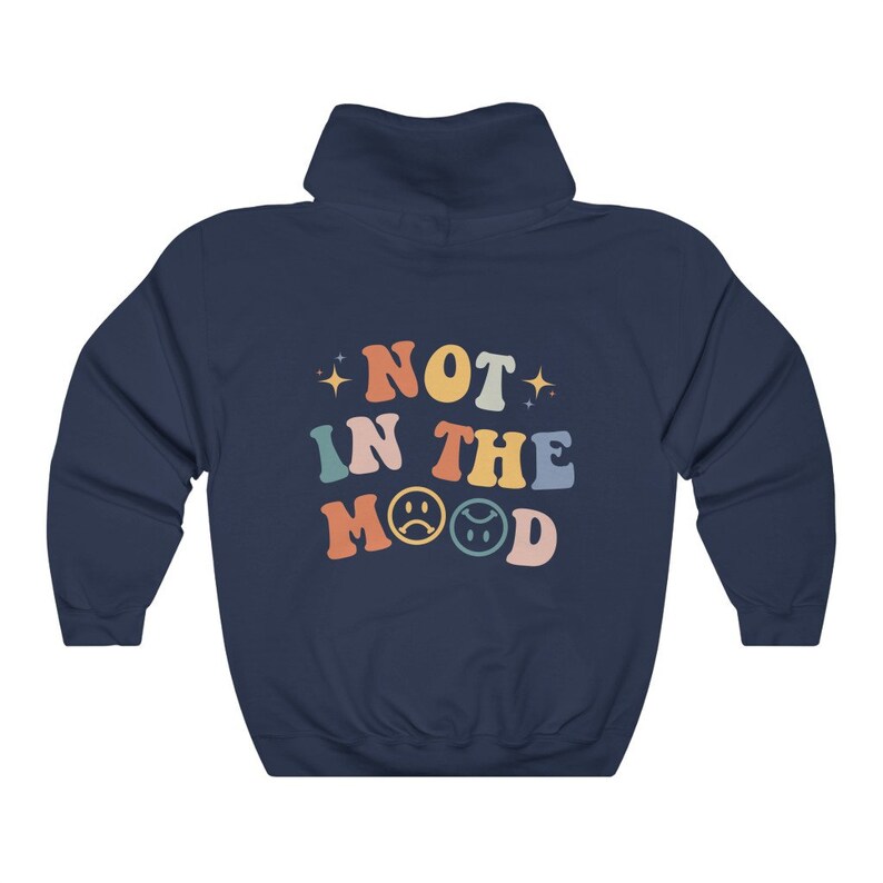 Pu&ograve; includere: Felpa con cappuccio blu navy con il testo "NOT IN THE MOOD" in colori arcobaleno con due emoji di faccina triste.