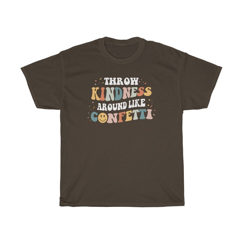 May include: A brown t-shirt featuring the text "Throw Kindness Around Like Confetti" in colourful retro lettering. The text is surrounded by confetti and a smiley face.