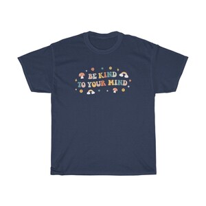 Puede incluir: Camiseta azul marino con un gr&aacute;fico colorido que dice "S&eacute; amable con tu mente". El gr&aacute;fico incluye hongos, arco&iacute;ris y estrellas.