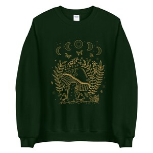 Op de afbeelding: Een donkergroen sweatshirt met een gouden omtrekillustratie van een paddenstoel, maanfasen, vlinders en bladeren.